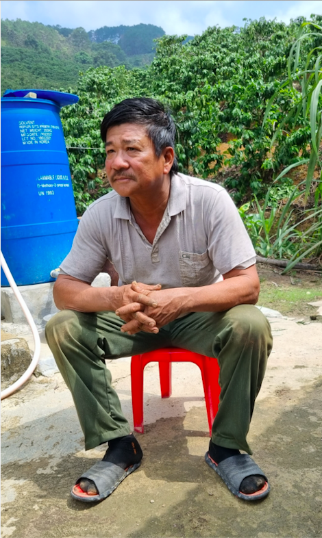 Decorative image from the Vietnam Project depicting a Vietnamese man sitting outside on a red stool, looking to the right behind the camera.